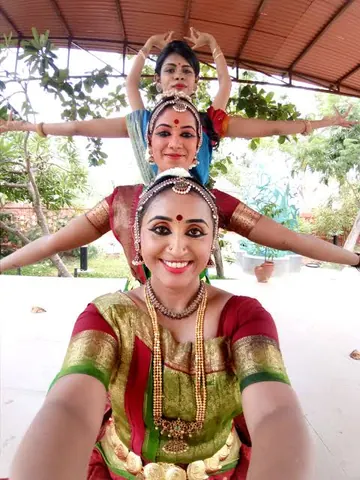 A photo of three Bharatanatyam dancers posed one behind the other